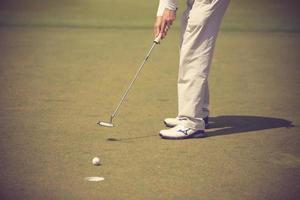 golfspelare på puttinggreen slår bollen i en hole.vintage färg foto