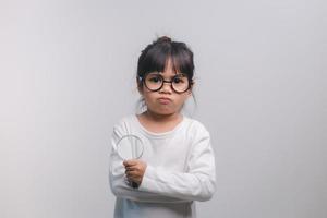 liten flicka barn håller ett förstoringsglas på vit bakgrund foto