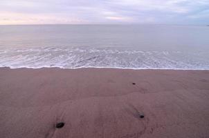 strand och våg vid soluppgången foto