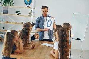 lära sig den nya o-bokstaven. grupp barn elever i klassen i skolan med lärare foto