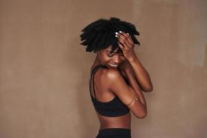 bara tillfredsställelse och positiva känslor. ung vacker afroamerikansk kvinna i studion mot brun bakgrund foto