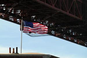 amerikanska flaggan vajar i vinden bredvid golden gate bridge i san francisco, kalifornien foto