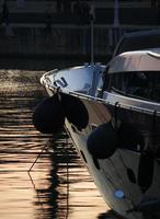 den nedgående solen lyser upp en yacht i hamnen i barcelona foto