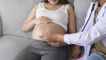 en läkare som håller stetoskop undersöker en gravid kvinna på sjukhuset, sjukvården och graviditetsvårdskonceptet foto