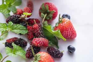 blandning av färska bär isolerade färska blåbär, mullbär, jordgubbar, myntabräda för kopia utrymme. hälsosamt koncept. rent ätande. foto
