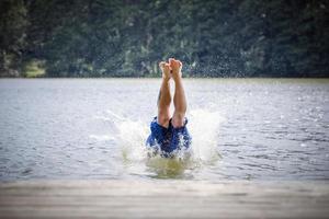 ung man dyker i en sjö. foto