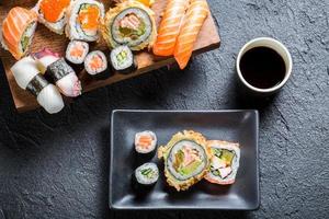 sushi serveras med sojasås på svart sten foto