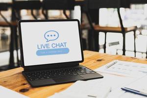 surfplattan sitter på ett skrivbord på en skärm och visar livechatttext och chattmarkörer, en konceptchatt i realtid med webbpersonal för att ställa frågor och svara på frågor. med systemet. kopieringsutrymme. foto