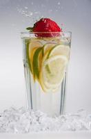 glas dryck med isbitar och frukter på vitt