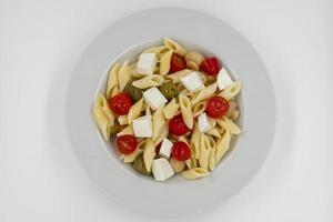 italiensk sommarsallad pasta fredda. fräsch och hälsosam sommarsallad på vit bakgrund. toppvy foto