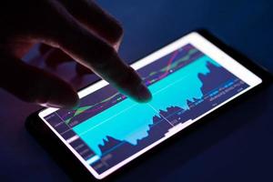 man touch indikatordiagram från aktiemarknaden på smartphone foto