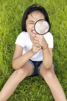 asiatisk liten flicka som håller ett förstoringsglas utomhus foto