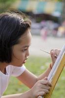 asiatisk liten flicka målning i parken foto
