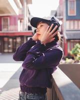 glad ung asiatisk kvinna som lyssnar på musik med hörlurar på gatan foto