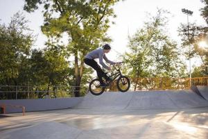 bmx ryttare tränar och gör tricks i street plaza, cykel stunt ryttare i cocncrete skatepark foto