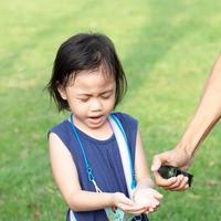 4 år gammal söt baby asiatisk flicka litet förskolebarn blundade när hennes far sprayade med alkohol foto