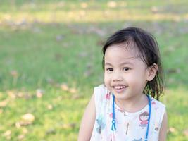 positiv charmig 4 år gammal söt asiatisk tjej, litet förskolebarn som ler och tittar åt vänster foto