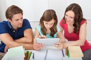 föräldrar som hjälper dotter att använda digital tablet