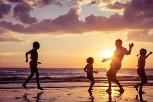 far och barn som leker på stranden foto