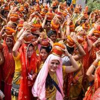 New Delhi, Indien 3 april 2022 - kvinnor med kalash på huvudet under jagannath-templet mangal kalash yatra, indiska hinduistiska hängivna bär jordkrukor som innehåller heligt vatten med en kokosnöt på toppen foto