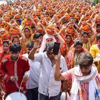 New Delhi, Indien 3 april 2022 - kvinnor med kalash på huvudet under jagannath-templet mangal kalash yatra, indiska hinduistiska hängivna bär jordkrukor som innehåller heligt vatten med en kokosnöt på toppen foto