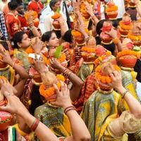 New Delhi, Indien 3 april 2022 - kvinnor med kalash på huvudet under jagannath-templet mangal kalash yatra, indiska hinduistiska hängivna bär jordkrukor som innehåller heligt vatten med en kokosnöt på toppen foto