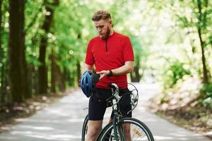 ta av skyddshjälmen. cyklist på en cykel är på asfaltvägen i skogen på en solig dag foto