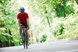 uthållighetstest. cyklist på en cykel är på asfaltvägen i skogen på en solig dag foto