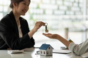 fastighetsmäklare som innehar husnyckel till sin klient efter att ha undertecknat kontraktsavtal på kontoret, koncept för fastigheter, flyttar hem eller hyr fastigheter foto