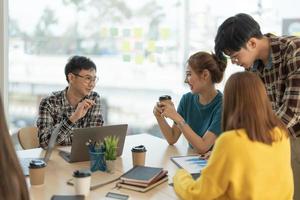 grupp av asiatiska företag diskuterar projekt på laptop kollega, arbetar tillsammans i par på delad arbetsplats, analyserar elektroniska dokument. foto