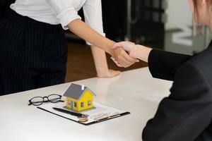 fastighetsmäklare och kund skakar hand efter att ha skrivit på ett kontrakt fastigheter, bostadslån och försäkringskoncept foto