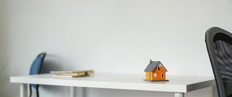 husmodell med fastighetsmäklare och kund diskuterar för kontrakt för att köpa hus, försäkring eller lån fastigheter bakgrund foto