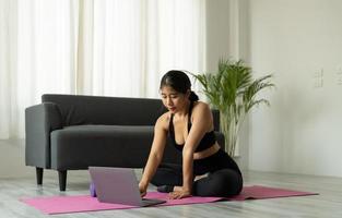asiatisk kvinna med bärbar dator på yogastudio - fitness, teknik och hälsosam livsstilskoncept