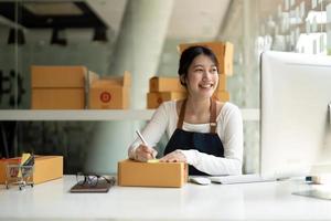 starta småföretagare frilans, porträtt ung asiatisk kvinna som arbetar hemmakontor med dator, online, marknadsföring, förpackning, leverans, SM, e-handelskoncept foto