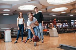 äntligen är det min tur. unga glada vänner har kul i bowlingklubben på sina helger foto