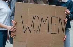 håller stor affisch. grupp feministiska kvinnor protesterar för sina rättigheter utomhus foto