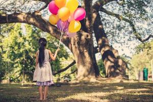 liten flicka med ballonger i ett fält foto