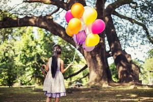liten flicka med ballonger i ett fält foto