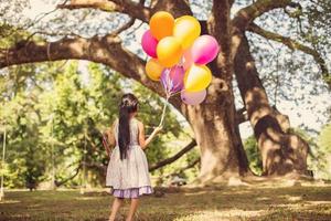 liten flicka med ballonger i ett fält foto