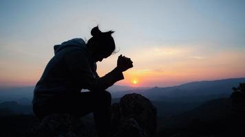 kristen kvinna ber tillbedjan vid solnedgången. händerna vikta i bön. dyrka gud med kristen koncept religion. foto