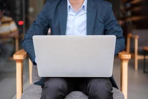 ung affärsman i kostym använder laptop, man skriver tangentbord dator anteckningsbok på kontor eller café. affärs-, teknik- och frilanskoncept foto