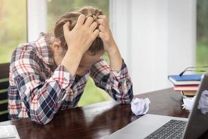 affärskvinna med huvudvärk när du arbetar med bärbar dator. stressad och deprimerad flicka röra hennes huvud, känna smärta när du sitter vid träbord, arbetsmisslyckande koncept foto