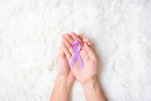 värld cancerdagen. kvinna hand hoy lavendel lila band för att stödja människor som lever och sjukdom. hälsovård och medicinsk koncept foto