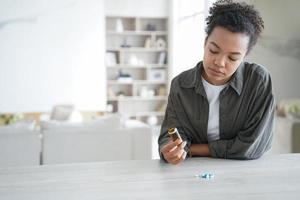 illa stressad afrikansk amerikansk tjej håller piller flacon. farmaceutisk behandling koncept. foto