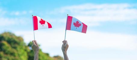 hand som håller Kanadas flagga på blå himmel bakgrund. Kanada dag och glada firande koncept foto
