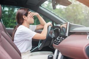 kvinna känner stress och arg under kör bil lång tid. asiatisk tjej trött och trötthet med huvudvärk sluta efter att ha kört bil i trafikstockning. sömnig, stretching och berusad koncept foto