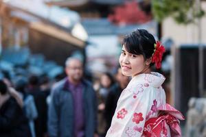 ung kvinna turist klädd i kimono njuta i yasaka pagodområdet nära kiyomizu dera tempel, kyoto, japan. asiatisk tjej med frisyr i traditionella japanska kläder under höstens lövverk säsong foto