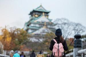 ensam kvinna turist reser på osaka slott under höstsäsongen, asiatisk resenär besök i osaka city, japan. semester, destination och resekoncept foto