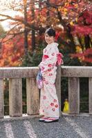 ung kvinna turist bär kimono njuter med färgglada löv i kiyomizu dera tempel, kyoto, japan. asiatisk tjej med frisyr i traditionella japanska kläder under höstens lövverk säsong foto