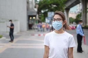 kvinna som bär medicinsk ansiktsmask under promenader på gatan och nattmarknaden, förhindrar coronavirus eller coronavirussjukdom. hälsa, livskoncept foto